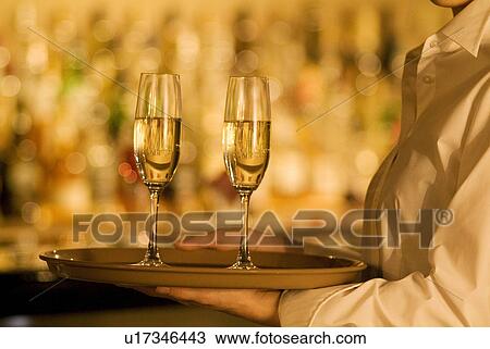 Waitress carrying champagne glasses View Large Photo Image Stock Image - Waitress carrying champagne glasses. Fotosearch