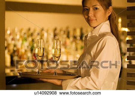 Waitress carrying champagne glasses View Large Photo Image Stock Photo - Waitress carrying champagne glasses. Fotosearch