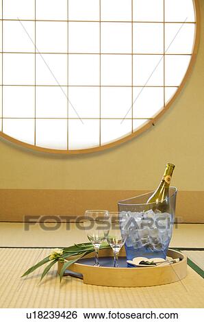 Stock Photograph - Wine bottle in ice bucket on tray with glasses and a flower in a Japanese room. Fotosearch