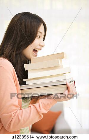 Picture - Woman carrying a stack of books. Fotosearch