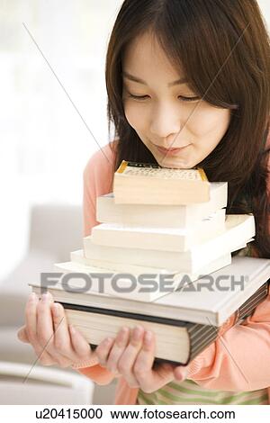 Stock Image - Woman carrying a stack of books. Fotosearch