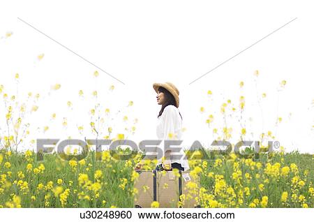 Woman carrying suitcase walking through a meadow View Large Photo Image Stock Image - Woman carrying suitcase walking through a meadow. Fotosearch