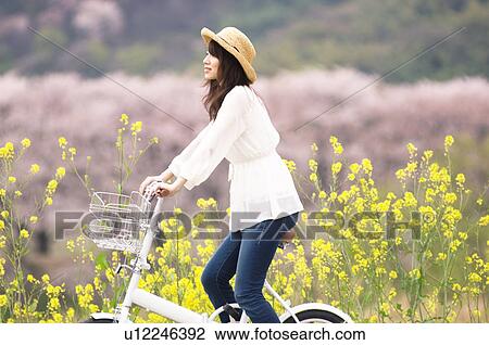 Stock Image - Woman cycling through spring landscape. Fotosearch
