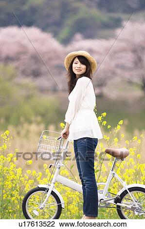 Stock Image - Woman cycling through spring landscape. Fotosearch