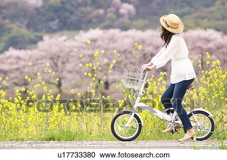 Stock Image - Woman cycling through spring landscape. Fotosearch