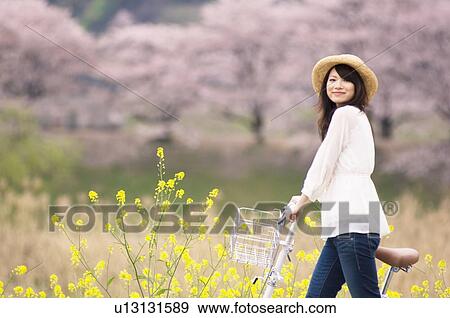 Stock Photo - Woman cycling through spring landscape. Fotosearch