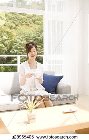Woman drinking tea on sofa in living room View Large Photo Image Stock Photography - Woman drinking tea on sofa in living room. Fotosearch