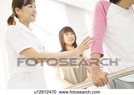 Stock Image - Woman encouraging her boyfriend with his rehabilitation. Fotosearch