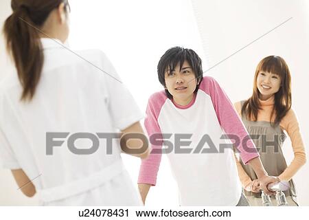 Stock Image - Woman encouraging her boyfriend with his rehabilitation. Fotosearch