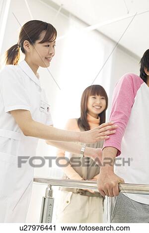 Stock Image - Woman encouraging her boyfriend with his rehabilitation. Fotosearch