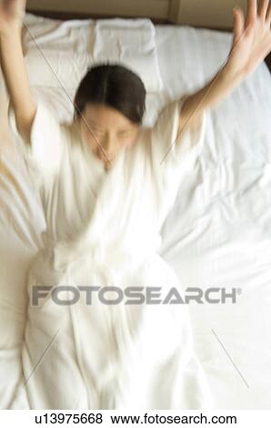 Stock Photo - Woman jumps backwards onto a bed. Fotosearch