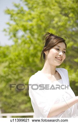 Stock Image - Woman leaning against a railing. Fotosearch