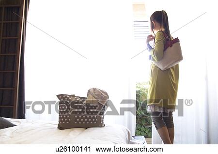 Woman looking out hotel room window View Large Photo Image Stock Image - Woman looking out hotel room window. Fotosearch