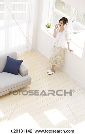 Stock Image - Woman on the phone in living room. Fotosearch
