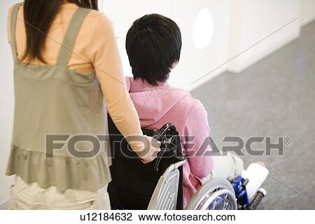 Woman pushing her boyfriend who is in a wheelchair View Large Photo Image Stock Image - Woman pushing her boyfriend who is in a wheelchair. Fotosearch