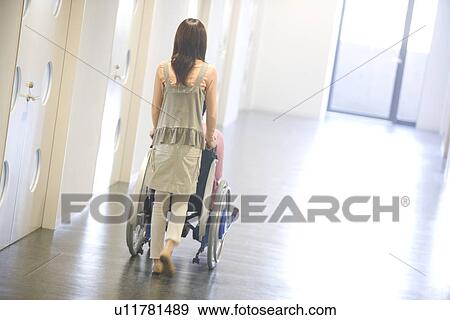 Stock Photo - Woman pushing her boyfriend who is in a wheelchair. Fotosearch