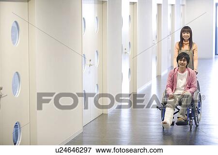 Stock Photo - Woman pushing her boyfriend who is in a wheelchair. Fotosearch