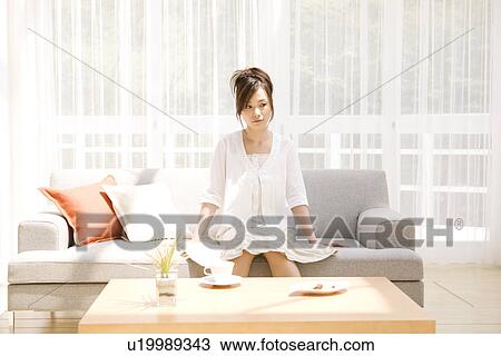 Woman sitting on sofa in living room View Large Photo Image Stock Image - Woman sitting on sofa in living room. Fotosearch