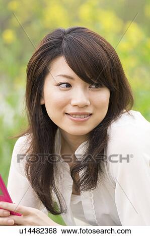 Stock Photo - Woman texting on cellphone in a meadow. Fotosearch