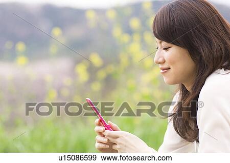 Woman texting on cellphone in a meadow View Large Photo Image Stock Photo - Woman texting on cellphone in a meadow. Fotosearch