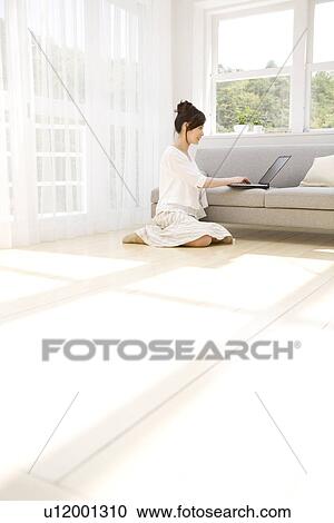 Woman using laptop in living room View Large Photo Image Stock Image - Woman using laptop in living room. Fotosearch