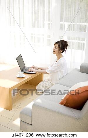 Woman using laptop in living room View Large Photo Image Stock Photograph - Woman using laptop in living room. Fotosearch
