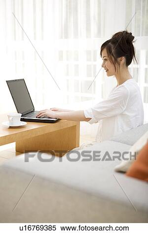 Woman using laptop in living room View Large Photo Image Stock Photography - Woman using laptop in living room. Fotosearch
