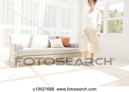 Stock Photo - Woman walking in living room. Fotosearch