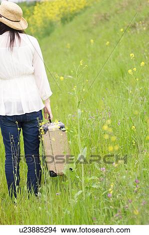 Woman walking through field carrying suitcase View Large Photo Image Picture - Woman walking through field carrying suitcase. Fotosearch