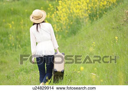 Woman walking through field carrying suitcase View Large Photo Image Picture - Woman walking through field carrying suitcase. Fotosearch
