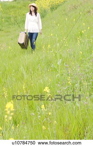 Woman walking through field carrying suitcase View Large Photo Image Stock Image - Woman walking through field carrying suitcase. Fotosearch