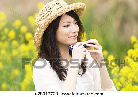 Woman wearing straw hat playing harmonica in a meadow View Large Photo Image Stock Image - Woman wearing straw hat playing harmonica in a meadow. Fotosearch