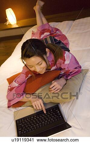 Woman wearing yukata lying on bed using laptop View Large Photo Image Stock Image - Woman wearing yukata lying on bed using laptop. Fotosearch
