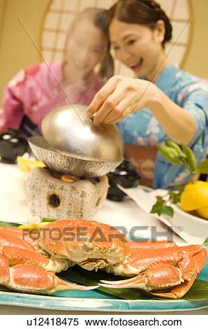 Stock Photography - Women dressed in yukatas sitting down to eat a meal. Fotosearch