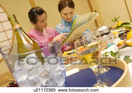 Stock Photo - Women sitting at table with meal, reading map. Fotosearch