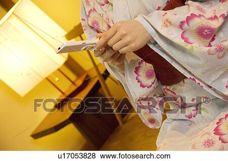 Stock Photo - Women wearing yukata texting on a mobile phone. Fotosearch