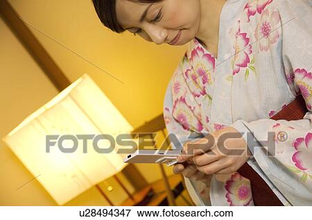 Women wearing yukata texting on a mobile phone View Large Photo Image Stock Photo - Women wearing yukata texting on a mobile phone. Fotosearch