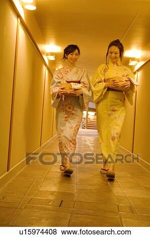 Stock Photo - Women wearing yukata walking down a hallway of a health spa carrying spa products in bamboo buckets. Fotosearch