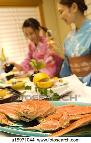 Picture - Women wearing yukatas sitting at table with seafood. Fotosearch