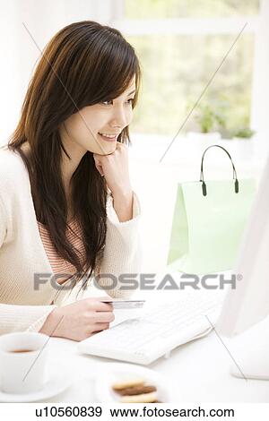 Stock Photo - Young woman shopping online. Fotosearch