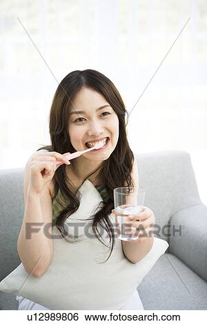 Young woman sitting brushing teeth View Large Photo Image Stock Photograph - Young woman sitting brushing teeth. Fotosearch