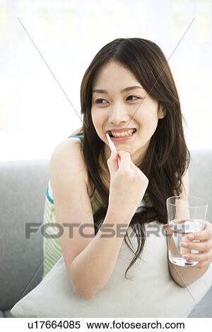 Stock Photography - Young woman sitting brushing teeth. Fotosearch