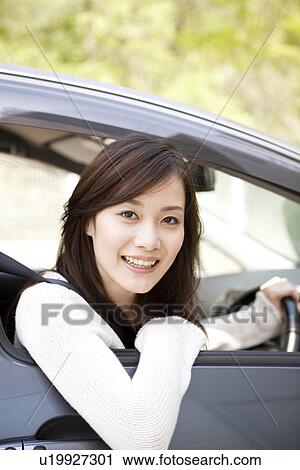 Stock Image - Young woman sitting in car. Fotosearch