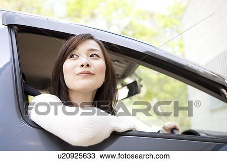 Stock Image - Young woman sitting in car. Fotosearch
