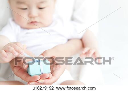 Stock Image - Baby and parent unwrapping a present. Fotosearch