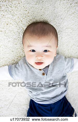 Stock Image - Baby boy lying on rug. Fotosearch