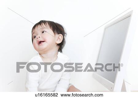 Stock Image - Baby boy next to computer screen. Fotosearch