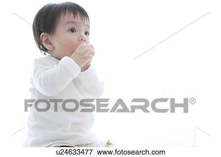 Stock Photo - Baby boy putting something in his mouth. Fotosearch