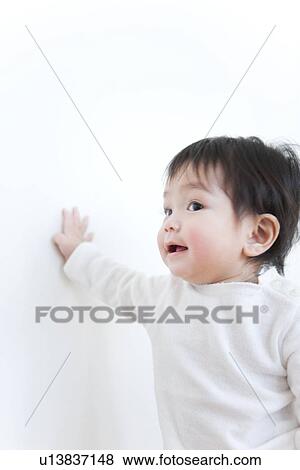 Stock Photo - Baby boy touching wall. Fotosearch