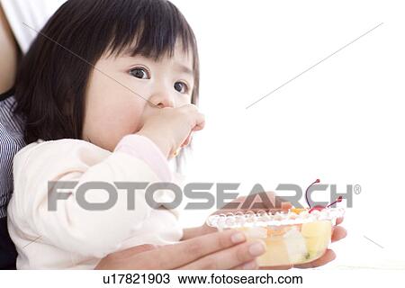Baby girl eating fruit salad on her mother's lap View Large Photo Image Stock Image - Baby girl eating fruit salad on her mother's lap. Fotosearch